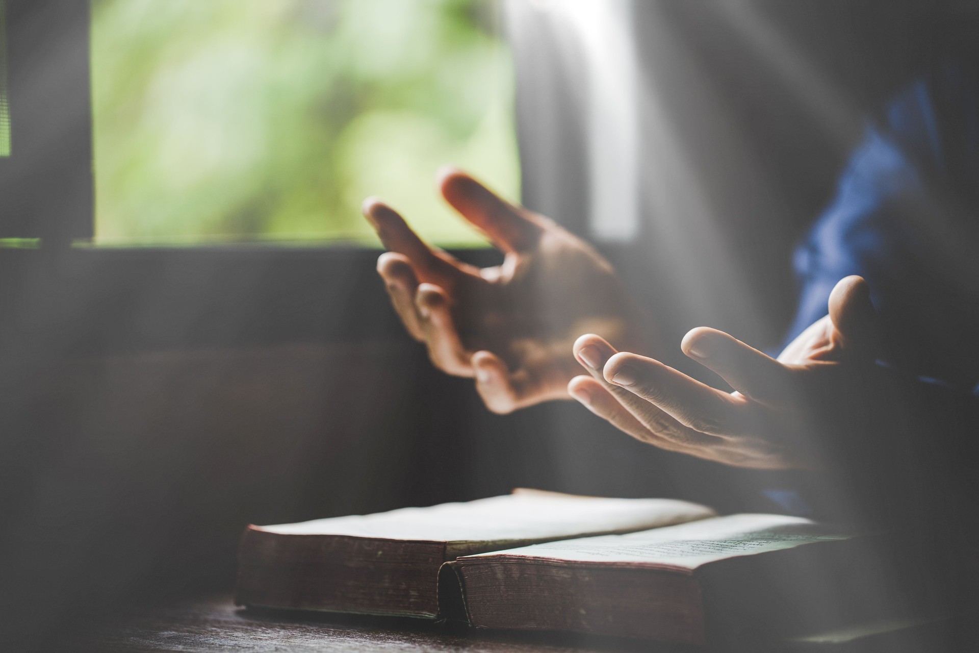 Hand folded in prayer to god on Holy Bible book in church concept for faith, spirituality and religion, woman person praying on holy bible in morning. christian catholic woman hand with Bible worship.